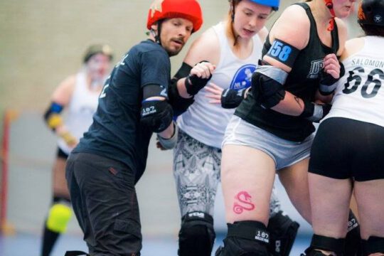 Animal, a male Jammer from team black is passing Blockers from team white during a scrimmage