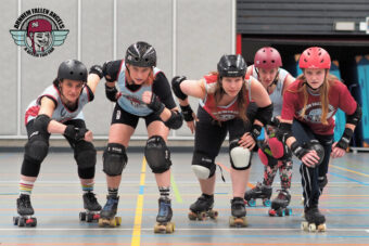 Five fierce looking roller derby players reday to sprint into action
